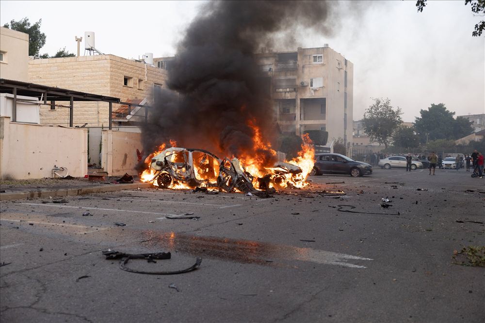 רכב עולה באש ועשן שחור ברחוב עירוני